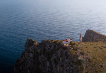 The lighthouse of Capo Palinuro at sunset with a view of the deep blue sea, Cilento, Campania, Italy.
